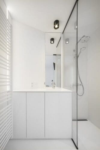 Minimalistische witte badkamer met douche en spiegel.