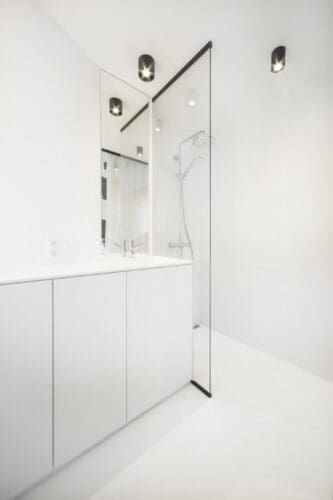 Minimalistische witte badkamer met glazen douchewand.